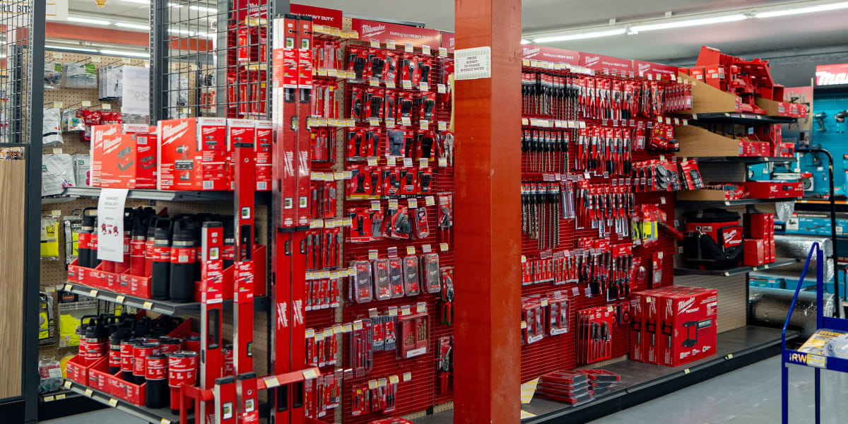 Interior view of the power tools department showing extensive displays of Milwaukee tools and accessories organized on red me