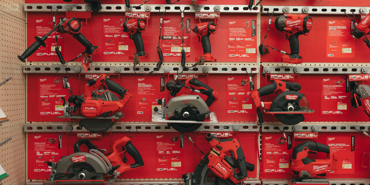 This image shows a well-organized Milwaukee tool display in a hardware store, featuring four shelves of red Milwaukee M18 FUE