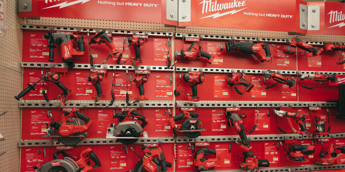 This image shows a comprehensive display of Milwaukee power tools mounted on a retail pegboard wall with prominent red Milwau