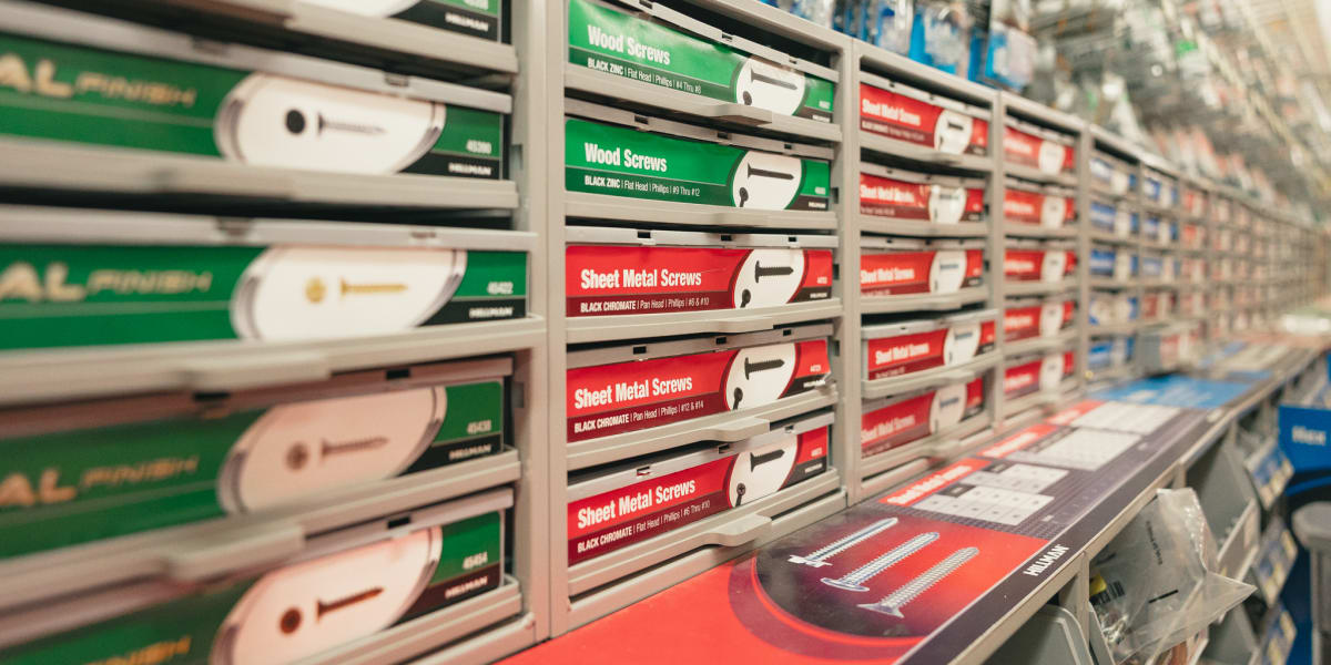 A hardware store aisle displaying organized rows of screws and fasteners in compartmentalized storage bins