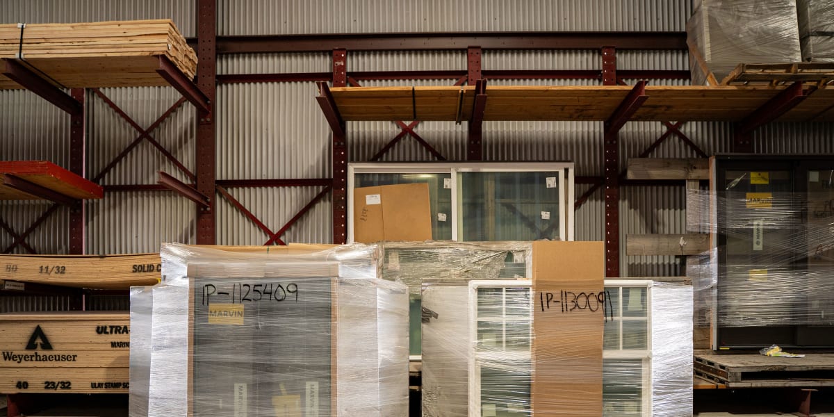 Wrapped and packaged windows stored on wooden pallets in a lumber yard warehouse setting