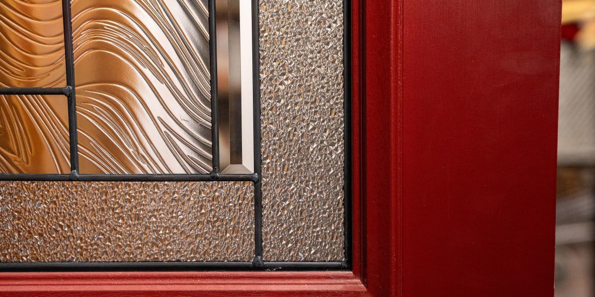 Close-up detail shot of a red window frame showing decorative glass panels with different textures and patterns