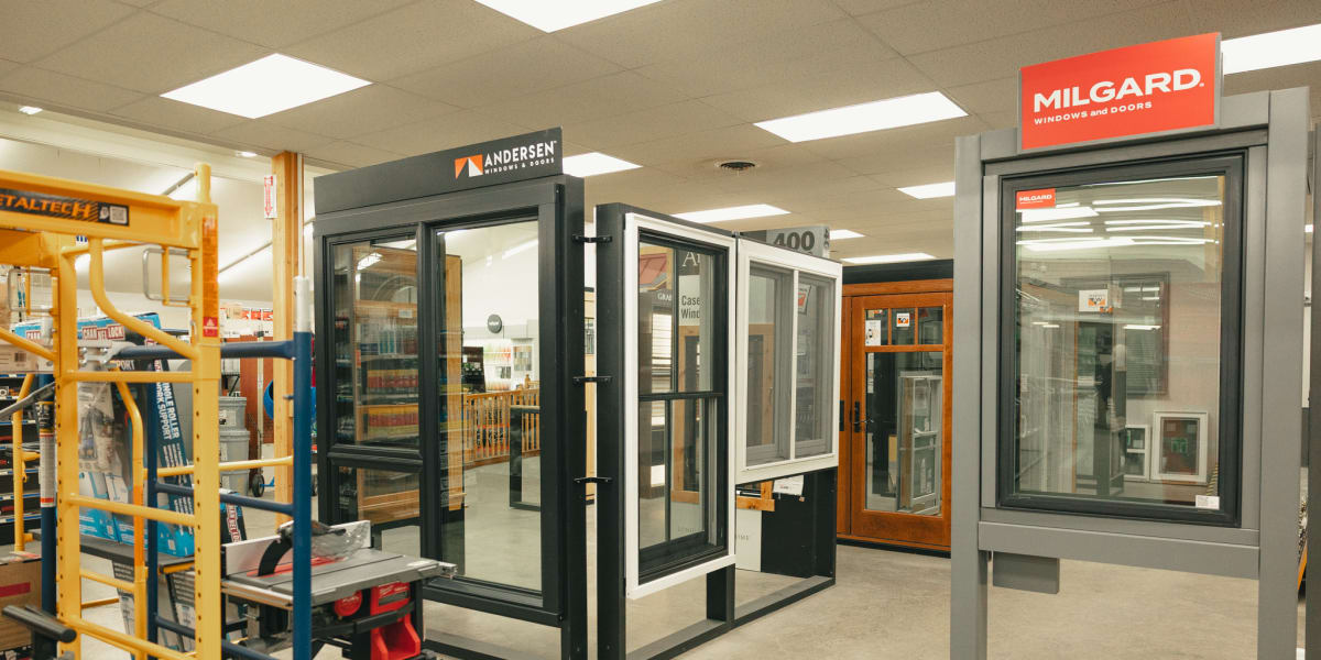 Interior showroom display featuring multiple window and door samples from major manufacturers