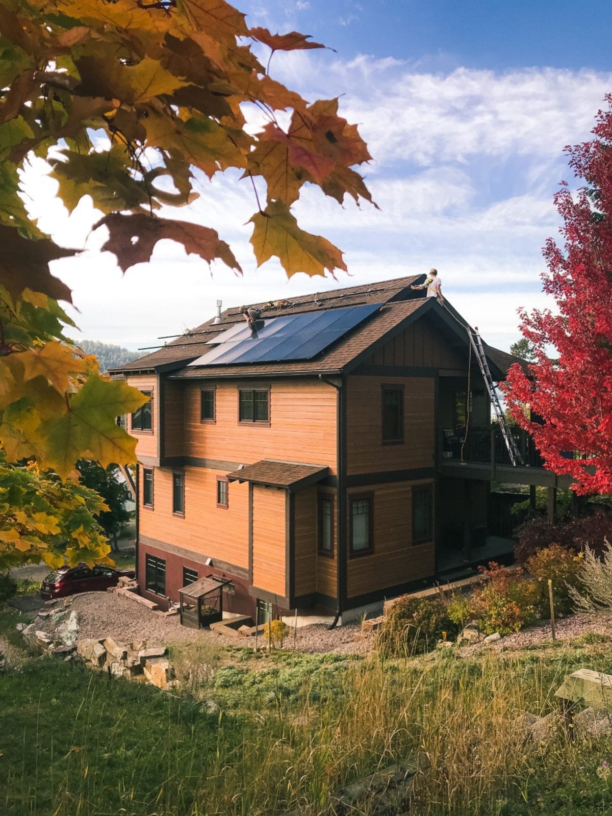 Northstone installers fitting a rooftop solar array on a cedar-sided Montana home in autumn