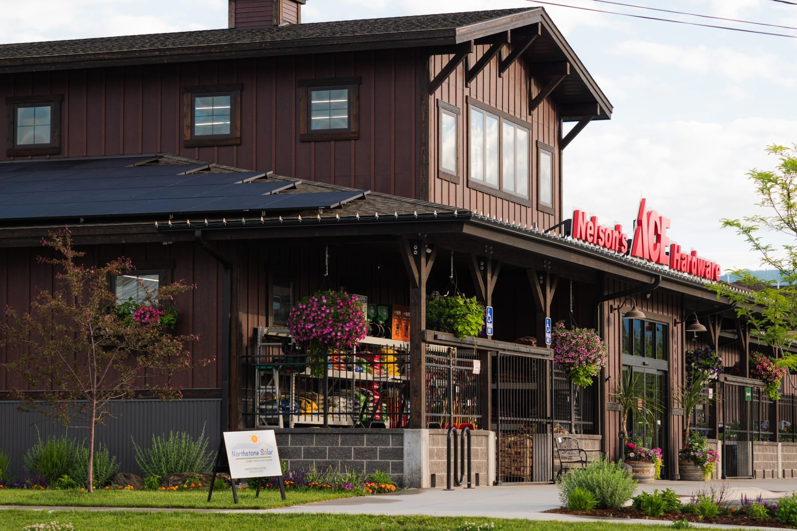 Rooftop solar array on Nelson's Ace Hardware in Whitefish, with a Northstone Solar sign in the garden out front