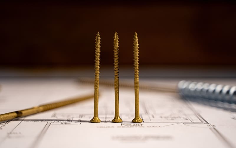 Brass screws and fasteners arranged on construction blueprints