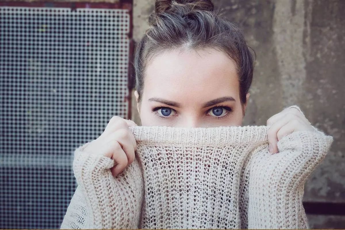 Woman in sweater peeking over collar, showcasing eye comfort