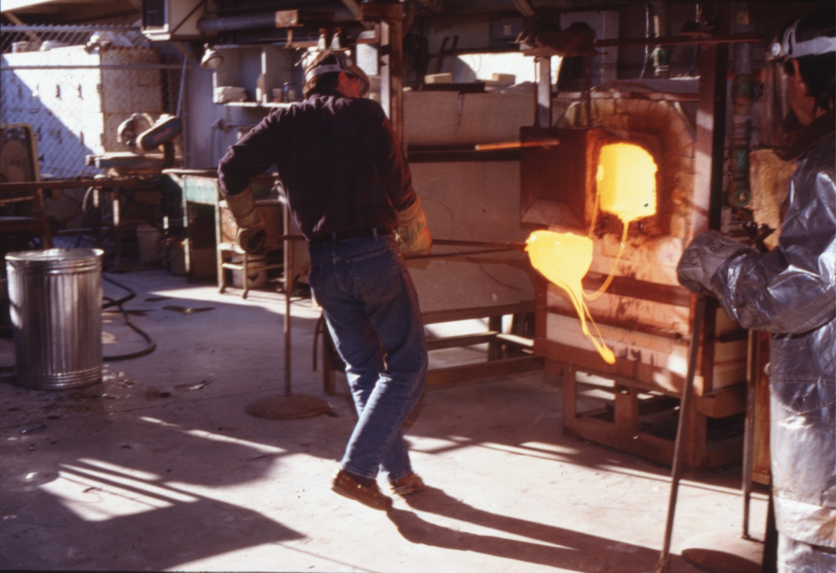 Lifting the hot glass sculpture from the flaming sand mold