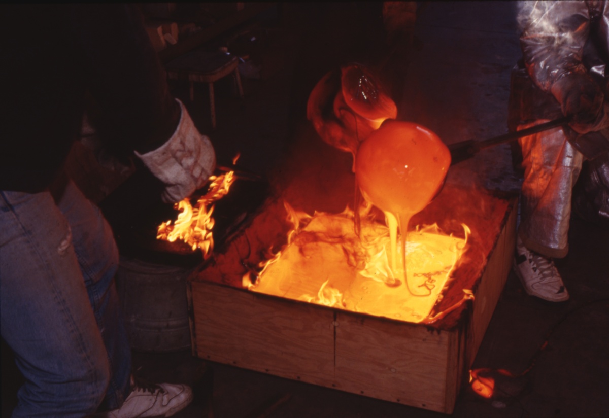 Pouring glowing molten glass into the prepared sand mold