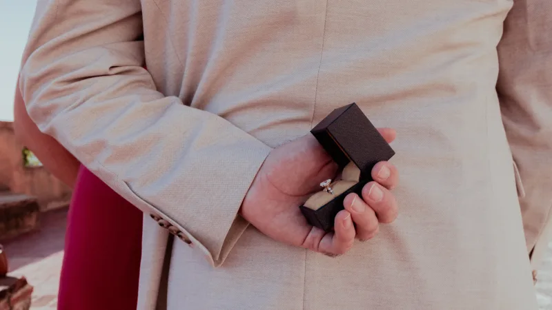 Proposal photography in Santo Domingo: hand holding black ring box, trembling hand detail, natural light moment