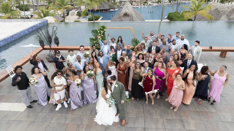 Wedding session with seventy guests in Punta Cana by a lagoon, bride in white and groom in sage green, professional wedding photographer