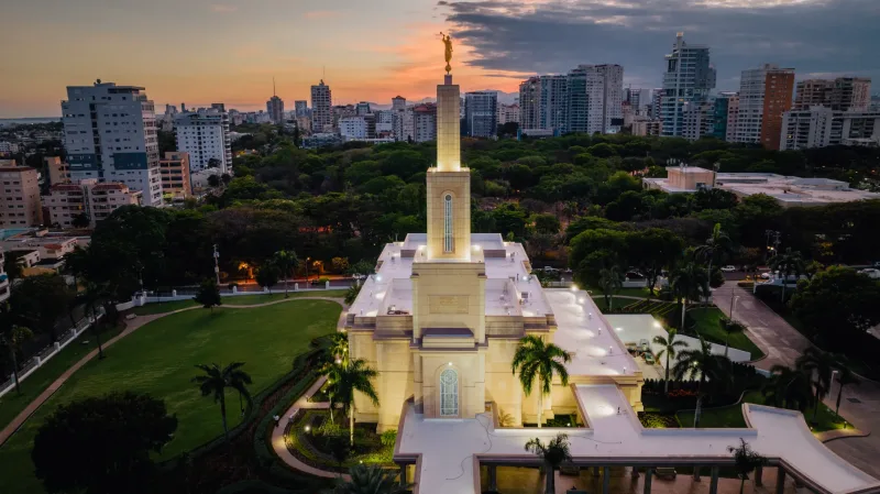 Aerial commercial photography of illuminated church at sunset in Santo Domingo with drone perspective, golden sky and city backdrop