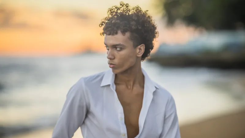 Luxury beach portrait at sunset: young man in white shirt facing the Atlantic Ocean in Santo Domingo