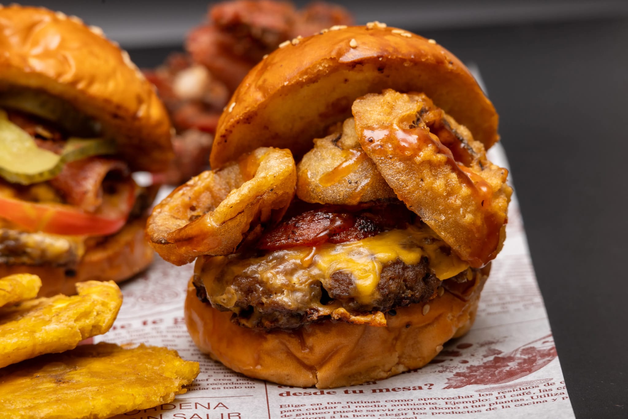 Burger stacked with crispy onion rings and sauce, close-up