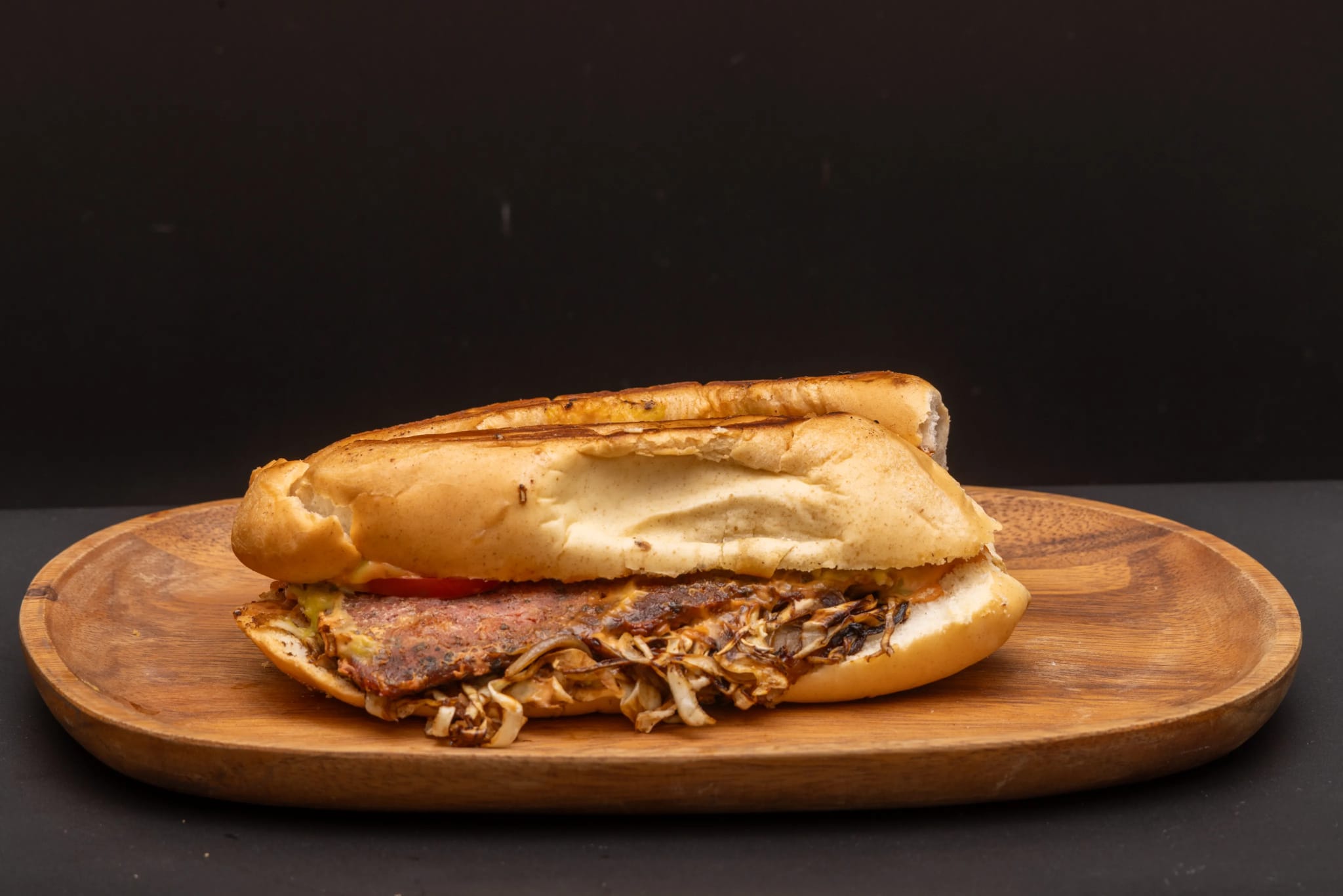 Grilled pulled-pork sandwich on a sub roll, served on a wood board