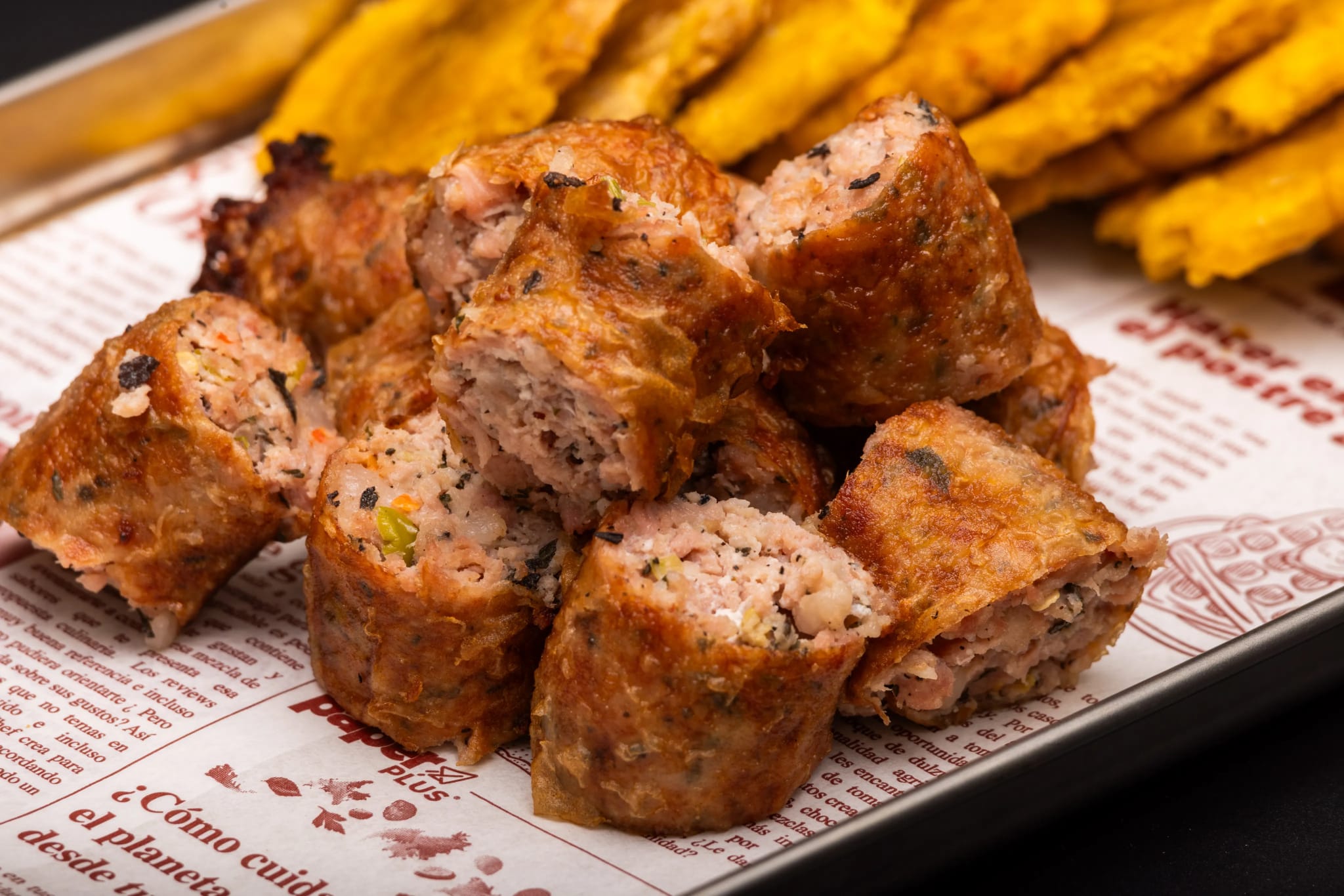 Fried meat croquetas on a branded newspaper-print tray with tostones