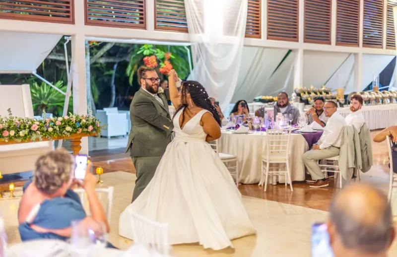 Pareja bailando la primera danza en salón de bodas elegante en Santo Domingo, con luz púrpura y vestido blanco fluido