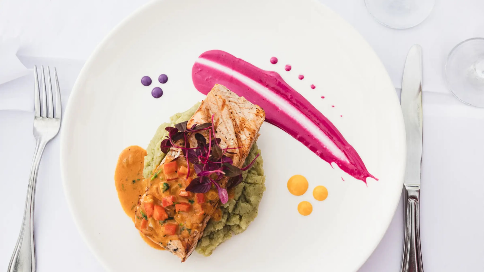 Entrada de filete de pescado sellado, montado artísticamente con acentos de salsa de colores