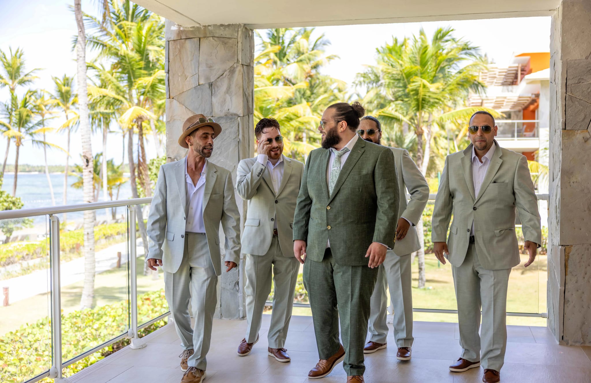 Novio caminando junto a cuatro padrinos con trajes verde salvia a juego en el resort