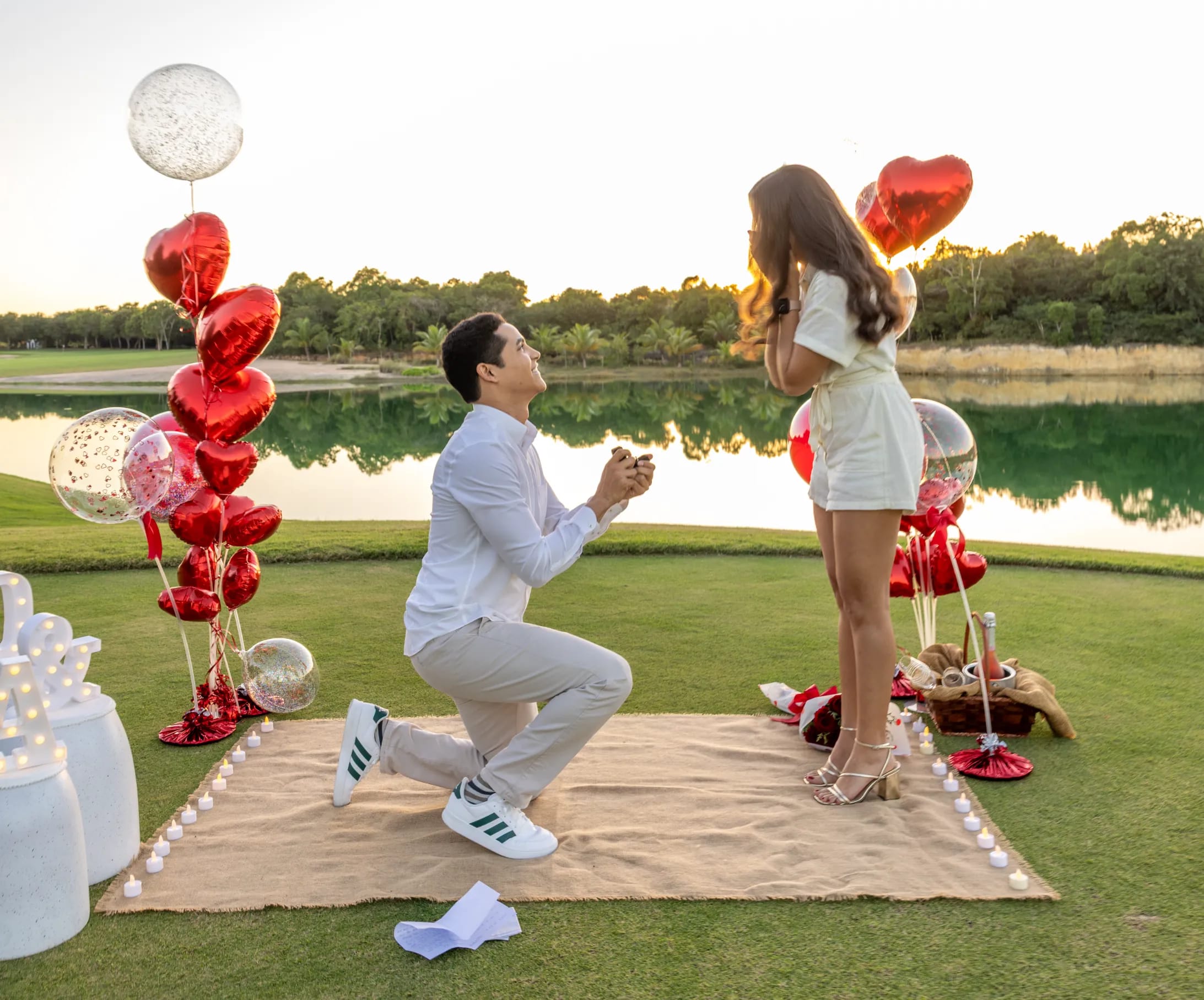 Hombre arrodillado proponiendo matrimonio junto a un lago en Punta Cana al atardecer