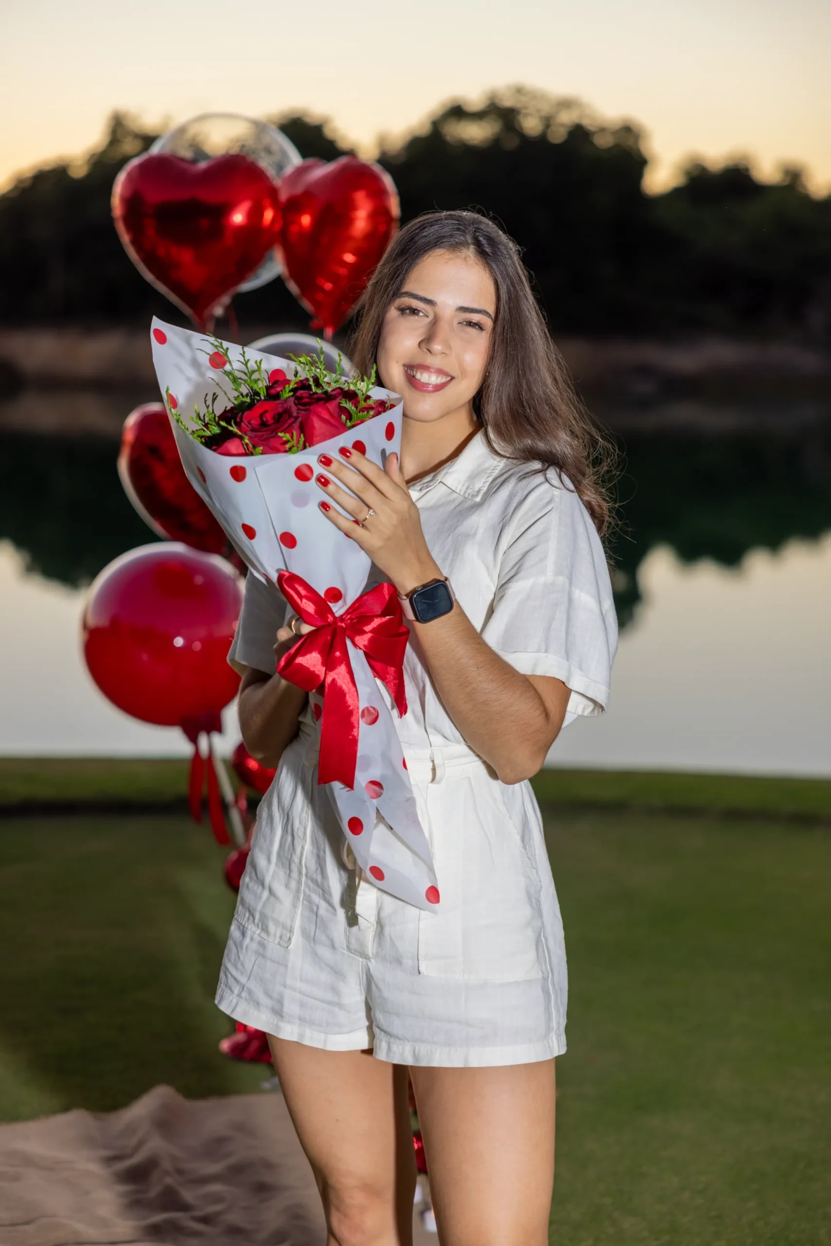 Futura novia posando con ramo de flores y globos de corazón tras la propuesta en Punta Cana