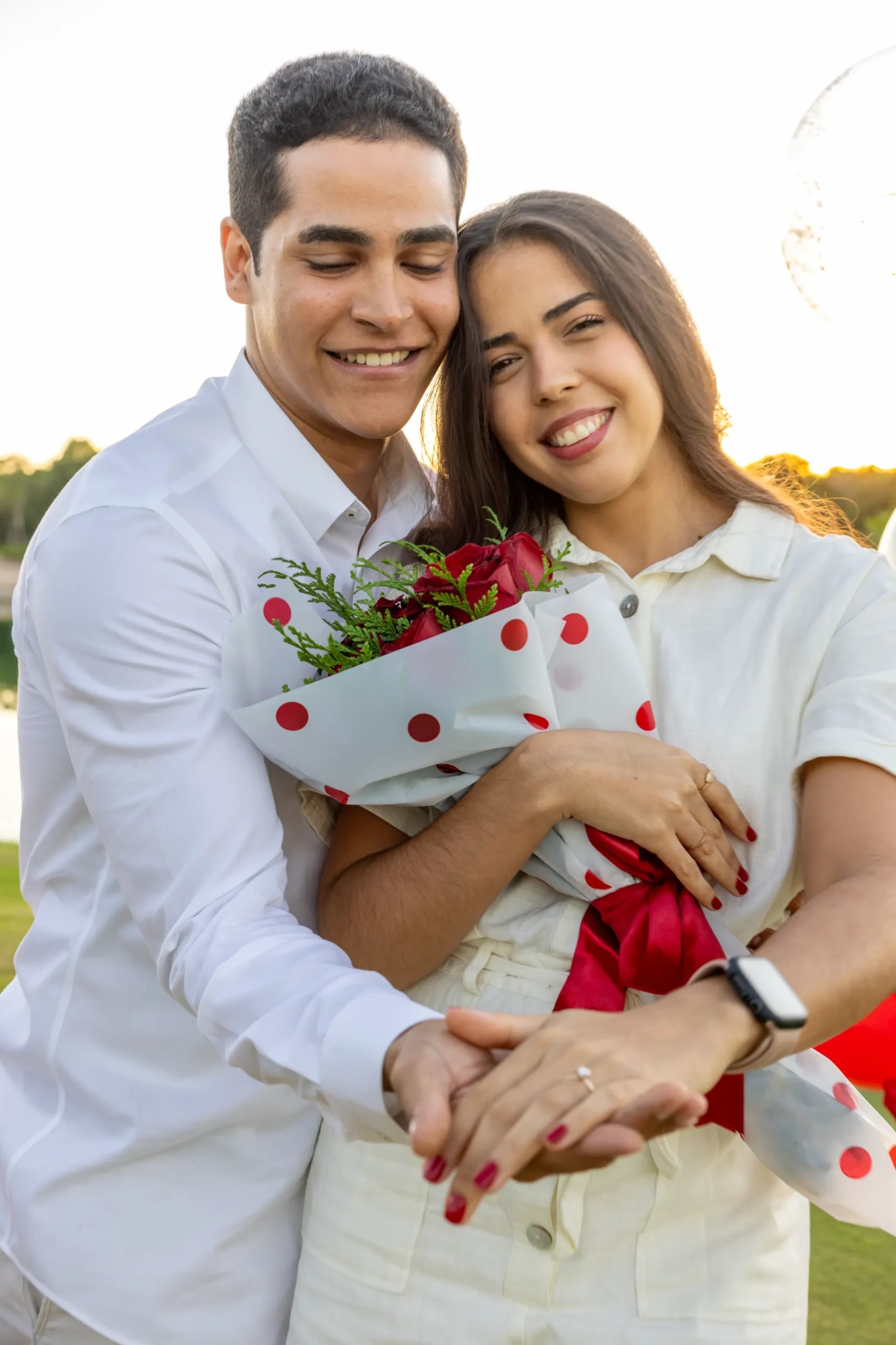 Pareja abrazada mostrando el ramo de flores y el anillo de compromiso en Punta Cana