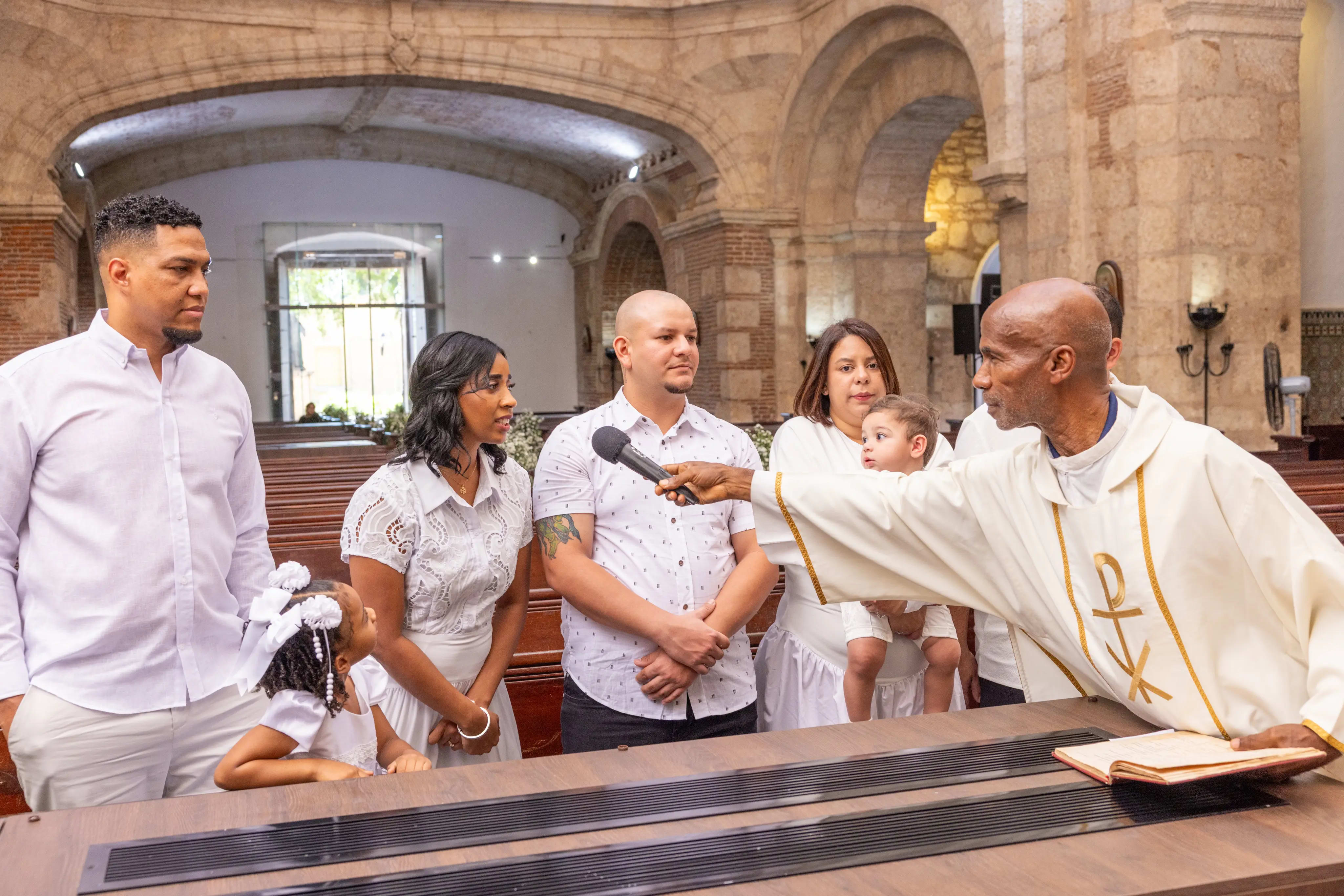 Toma amplia de la ceremonia de bautizo dentro de la nave de piedra de una iglesia colonial, familia extendida de blanco, Santo Domingo — Babula Shots