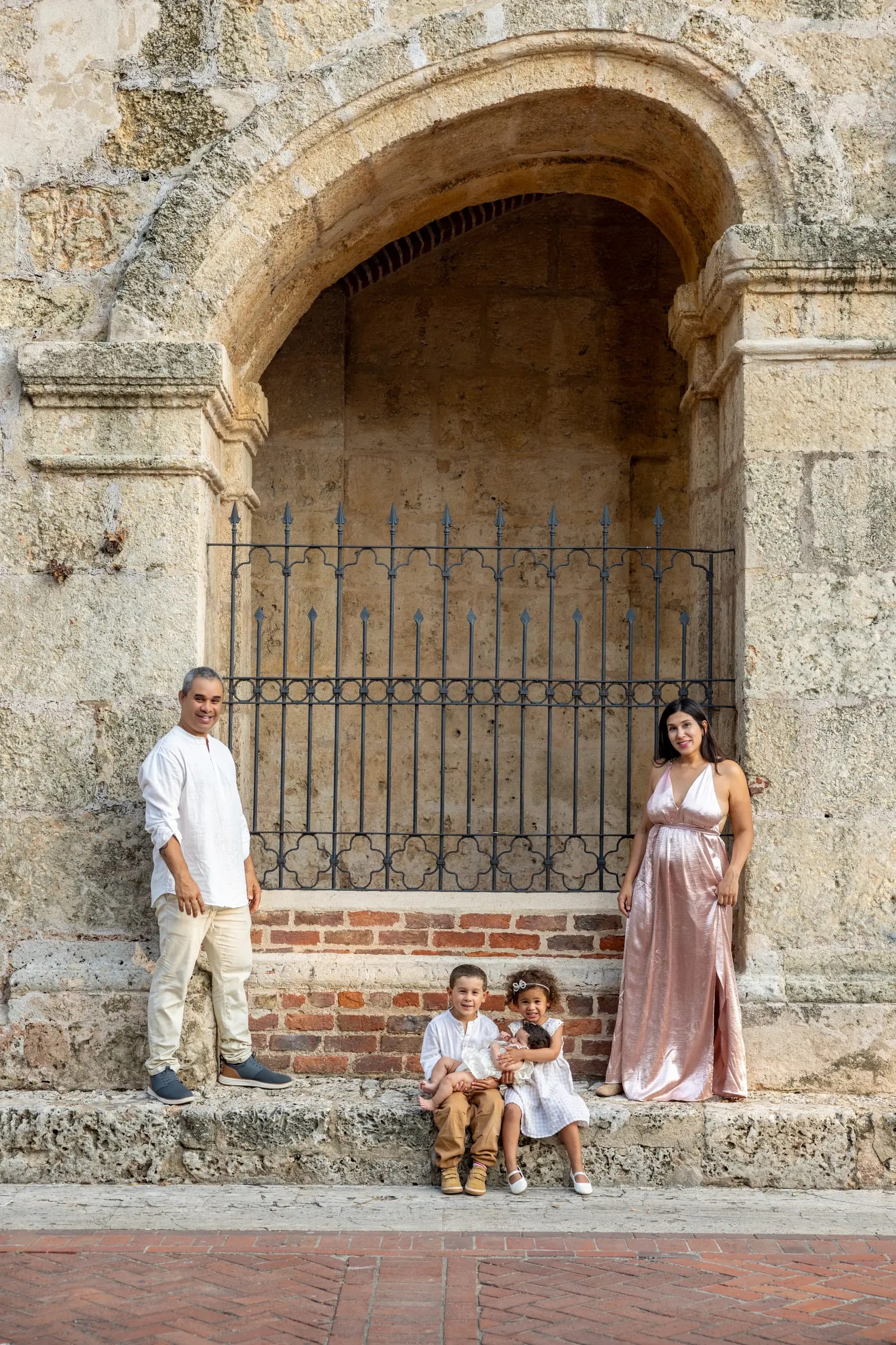 Retrato familiar bajo un arco de piedra con reja de hierro en la Zona Colonial, Santo Domingo — Babula Shots