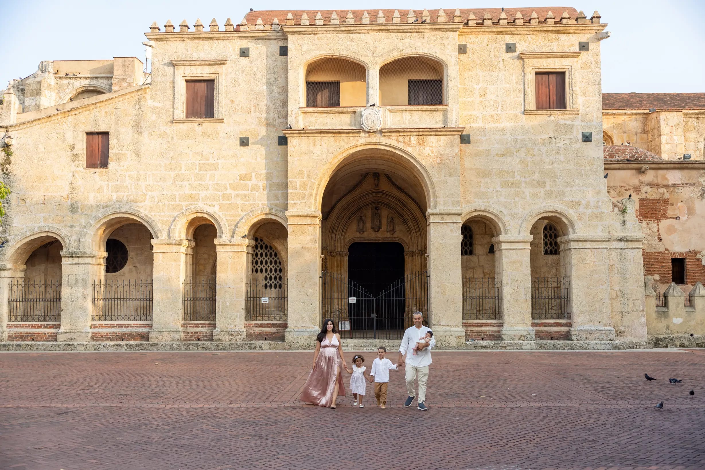 Familia caminando de la mano frente a la fachada de una gran catedral colonial, Santo Domingo — Babula Shots