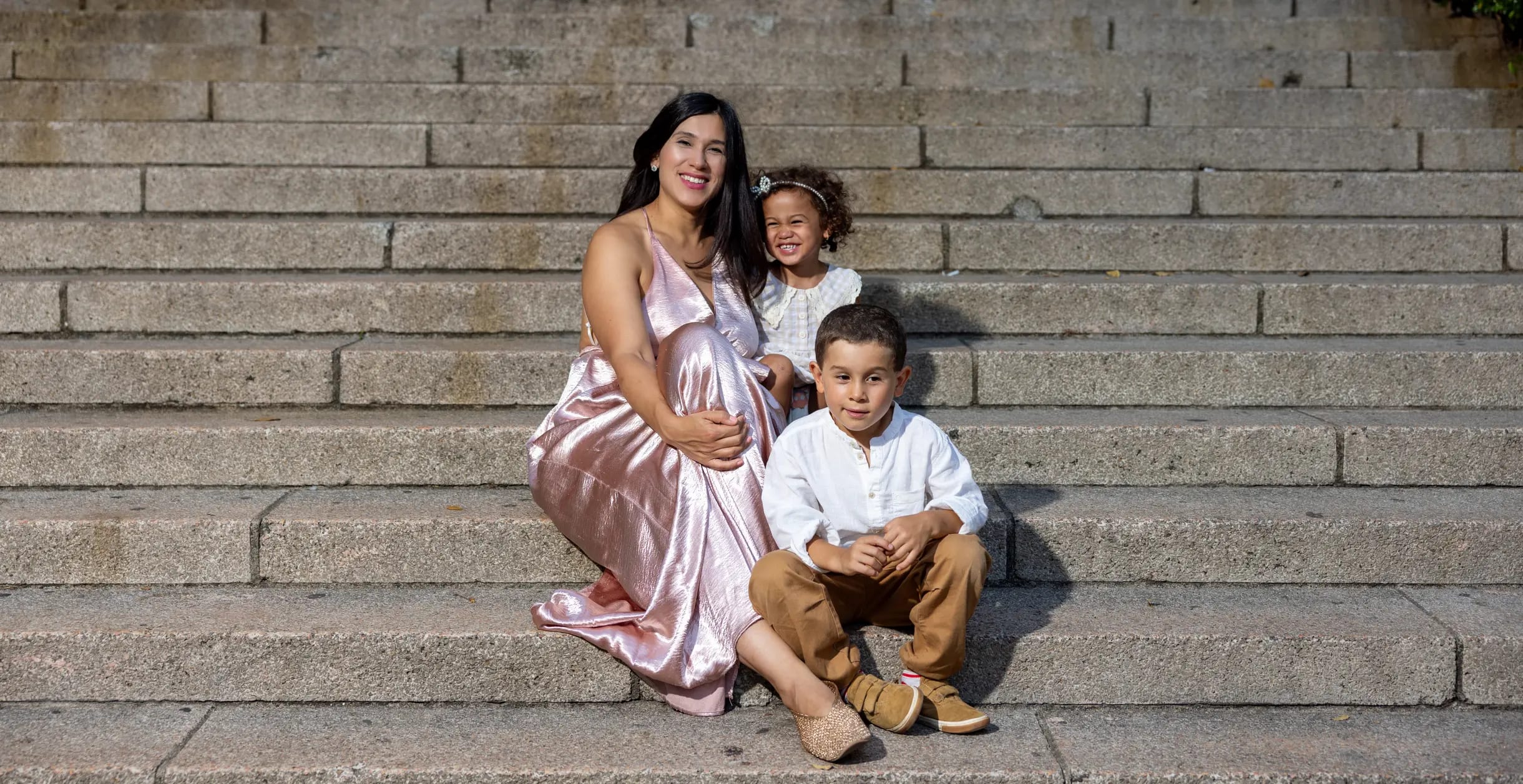 Madre abrazando a sus dos hijos en una escalinata de piedra colonial, Santo Domingo — Babula Shots