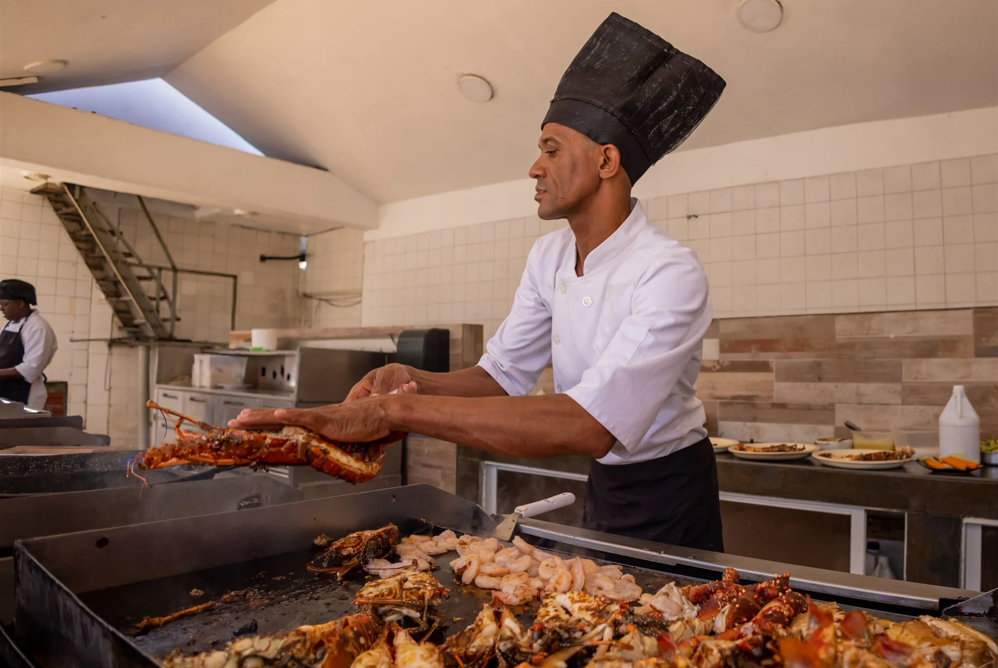 Chef holding a lobster fresh off the grill in the open kitchen
