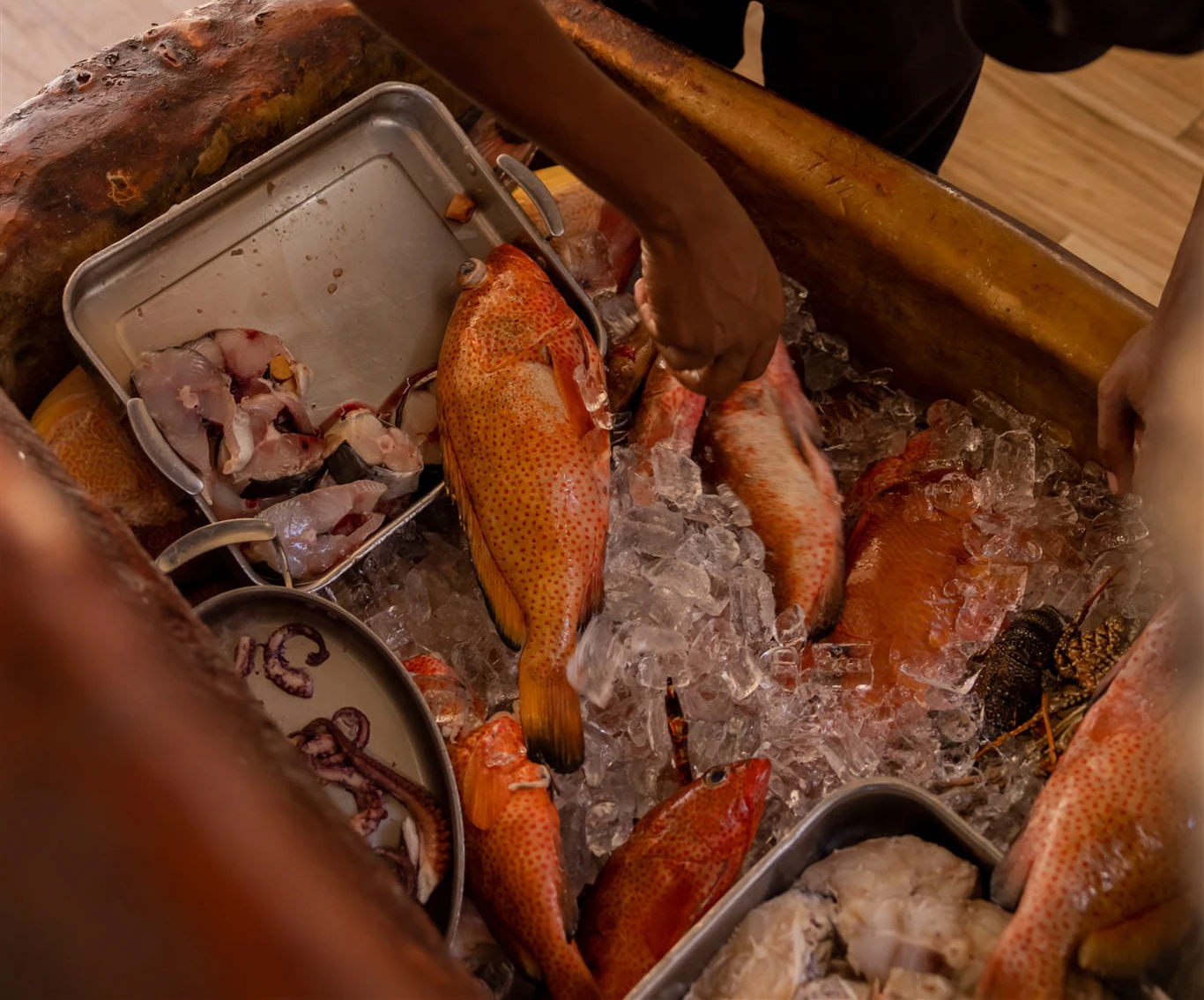 Two chefs preparing fresh lobster and crab on a prep table