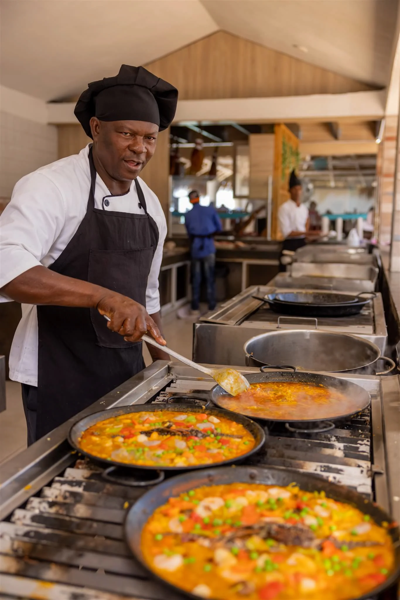 Chef cooking seafood paellas across several pans at once