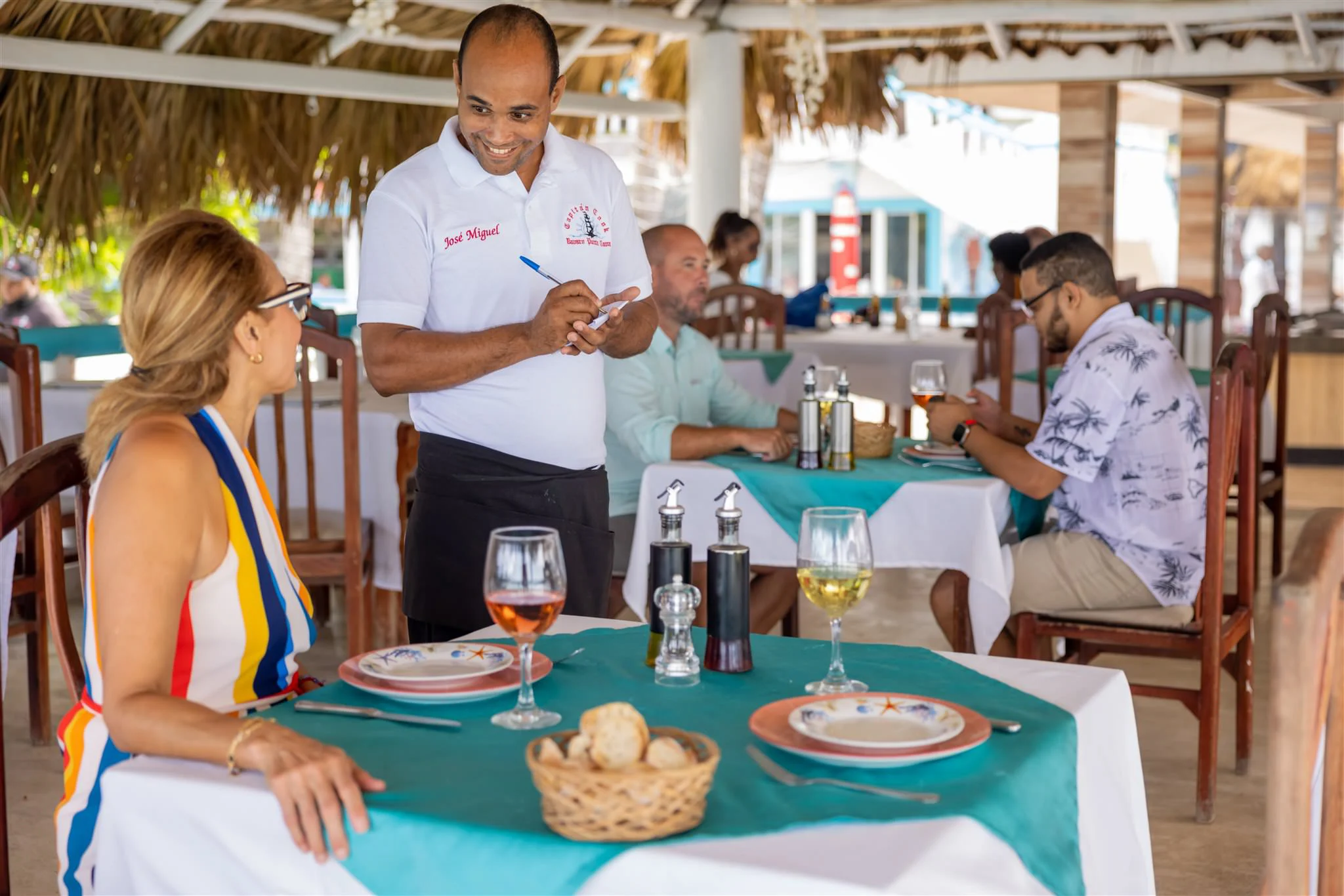 Waiter taking an order tableside under a palapa roof