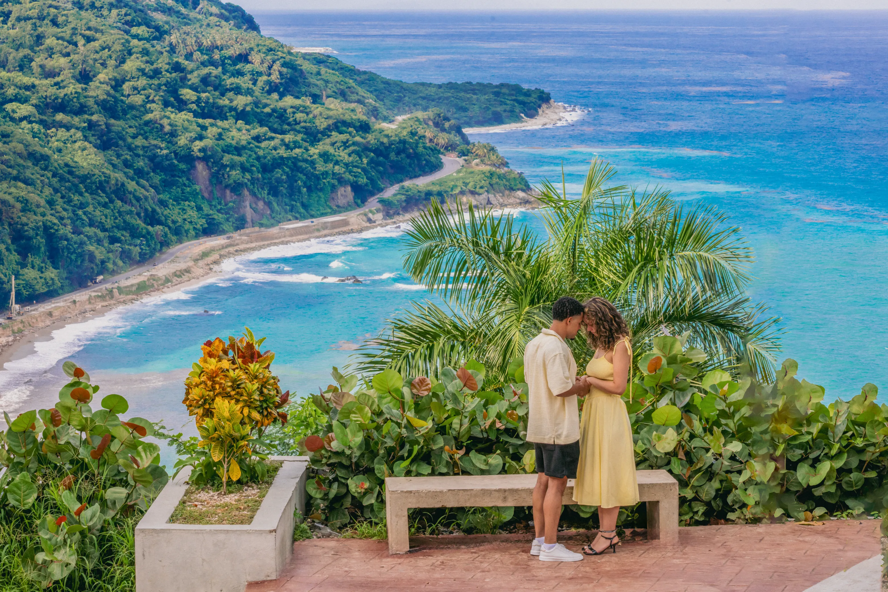 Vista amplia de una pareja abrazada en un mirador costero sobre el Mar Caribe, ruta Barahona–Pedernales, República Dominicana