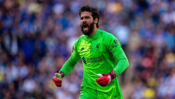 Alisson Becker berlari keluar dari gawang, mencoba menghalau serangan lawan, ekspresi fokus di tengah hujan