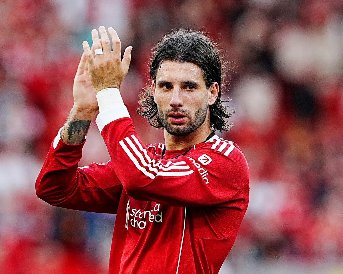 Dominik Szoboszlai merayakan gol, lengan terangkat, jersey nomor 8 berkibar di angin Anfield