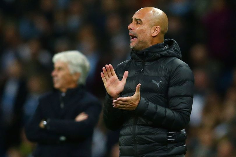 Pep Guardiola berdiri tegak di pinggir lapangan Etihad, latar belakang pemain Man City merayakan gol ke gawang Liverpool