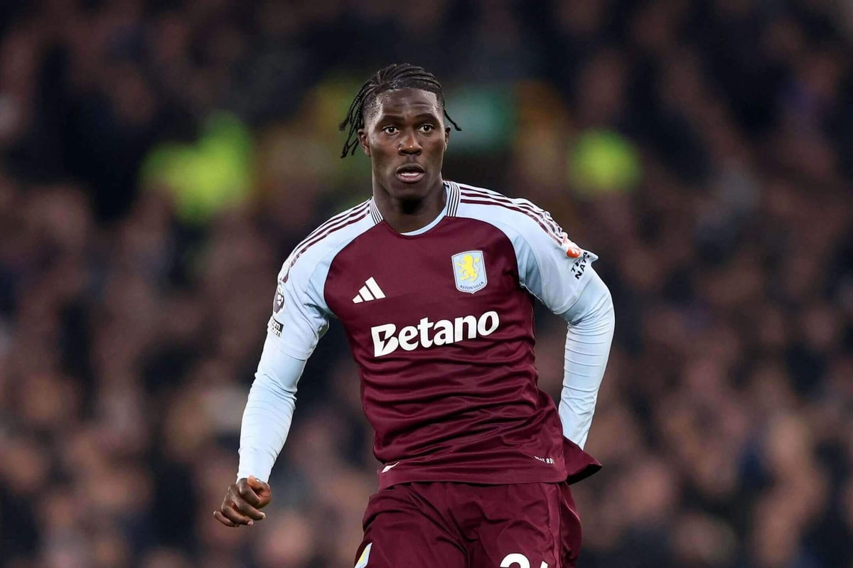 Amadou Onana merayakan gol untuk Aston Villa, lengan terangkat, jersey biru menyala di bawah lampu Villa Park