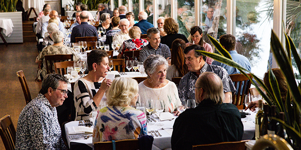 group of diners fill tables along the window in Alexander's sunroom for a wine dinner event