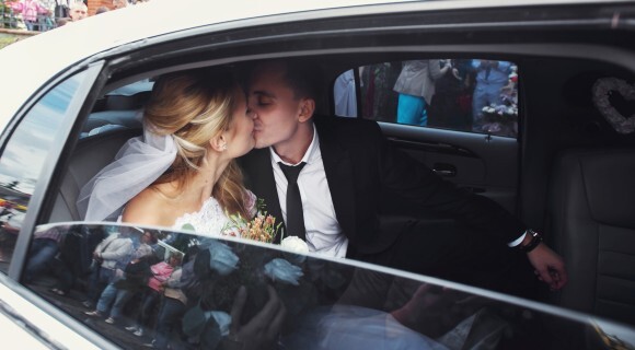 bride and groom kiss through the window of a car