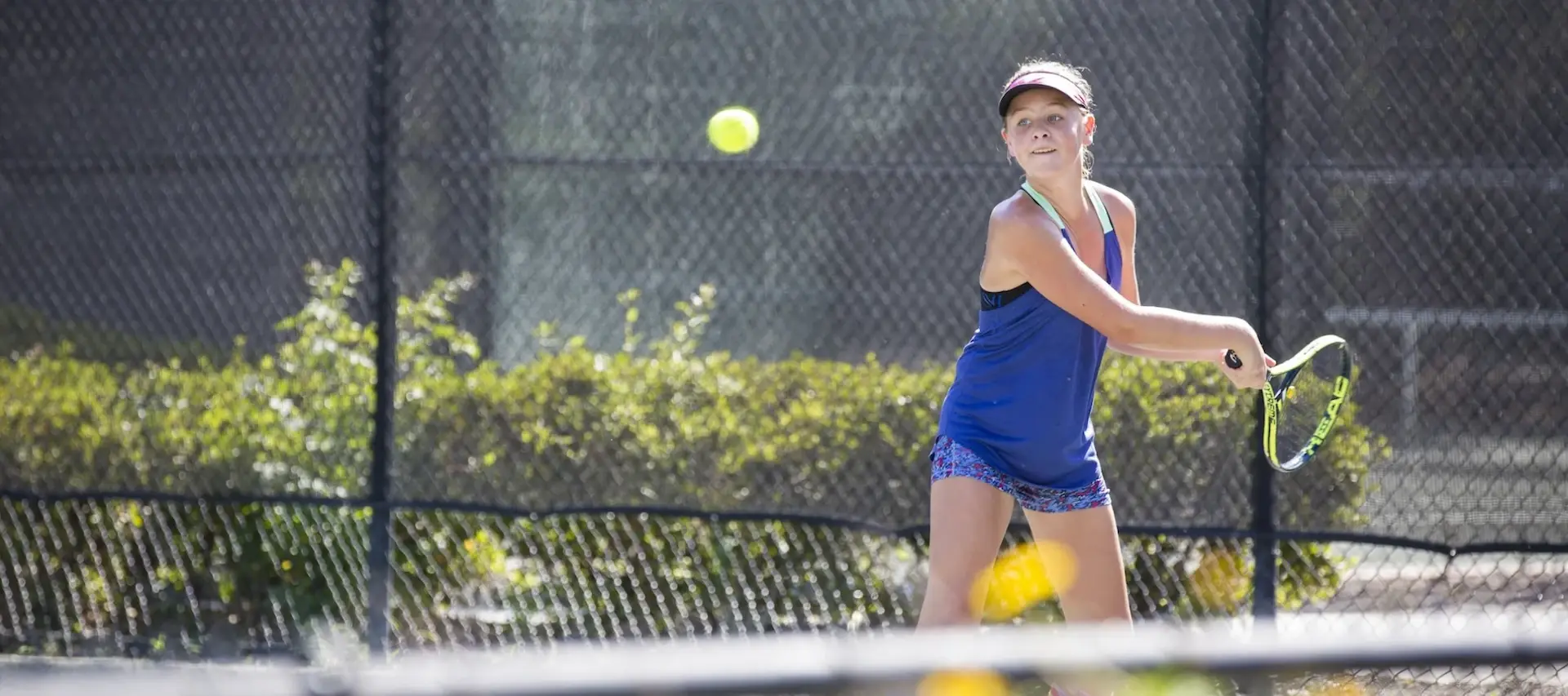 a young girl mid swing playing tennis at Palmetto Dunes Tennis center