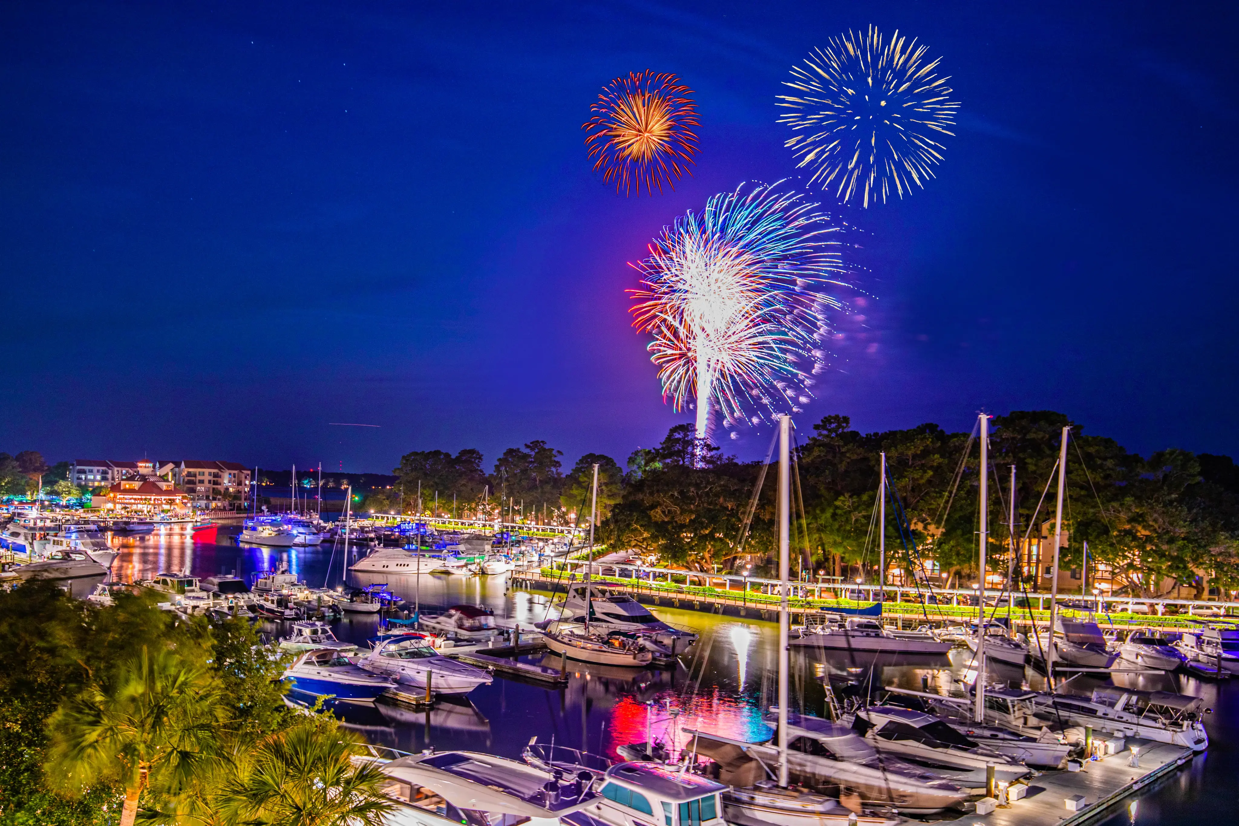 fireworks light up the sky over the marina at night