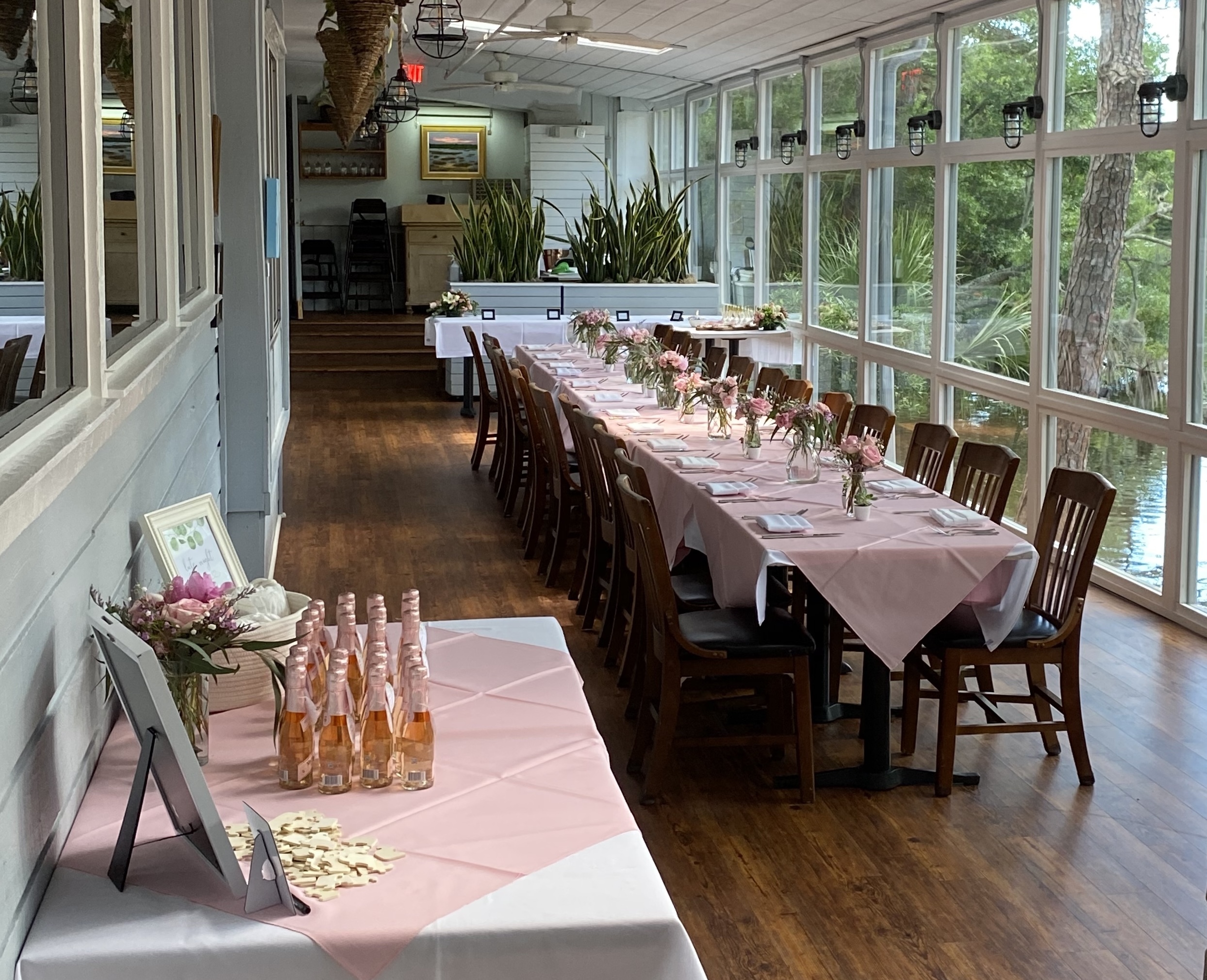 long table set up with pink tablecloth and centerpieces for an event in the sunroom of Alexander's