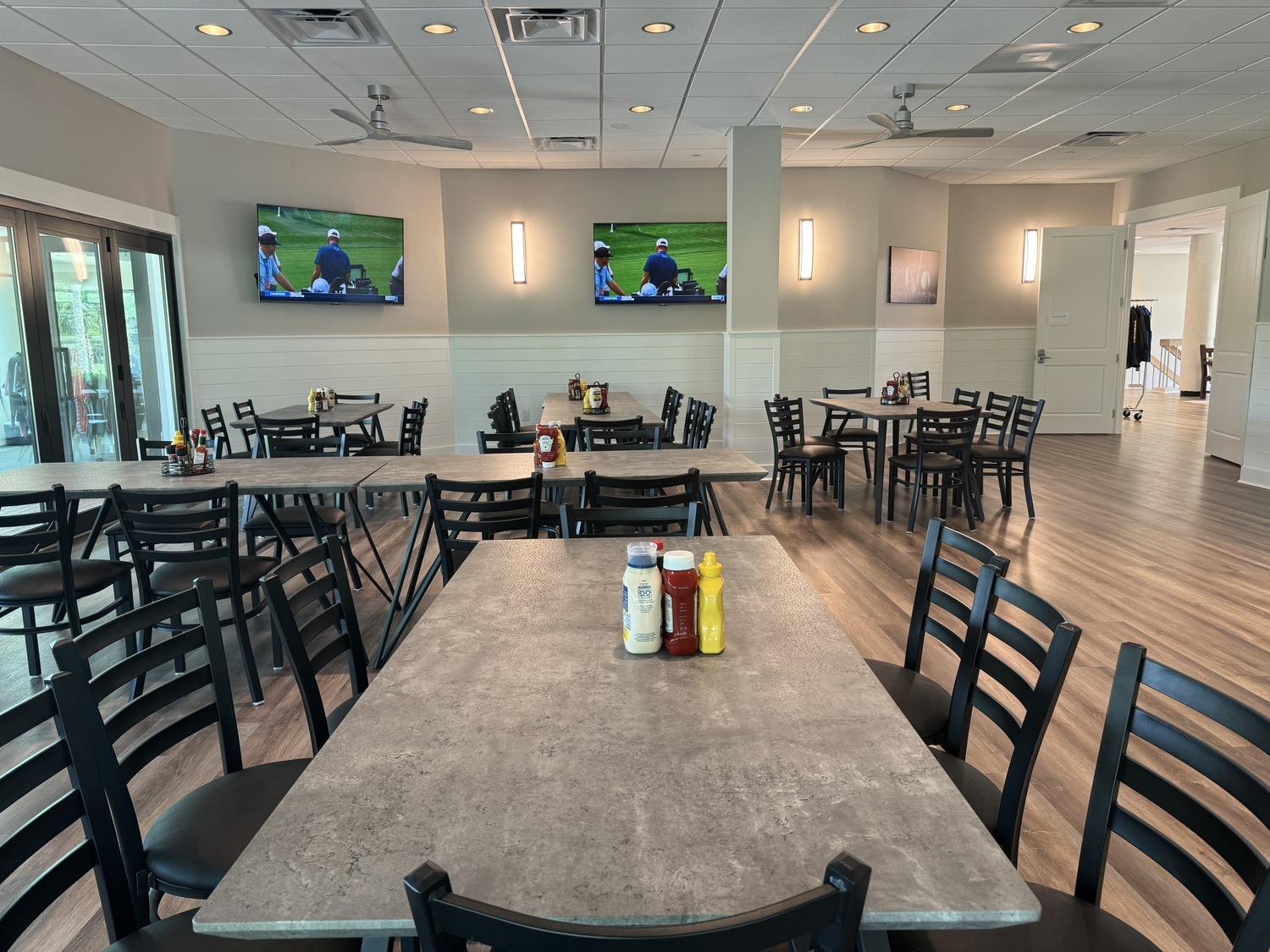 long tables and black chairs with tv setup and large windows at Arthur Hills grill