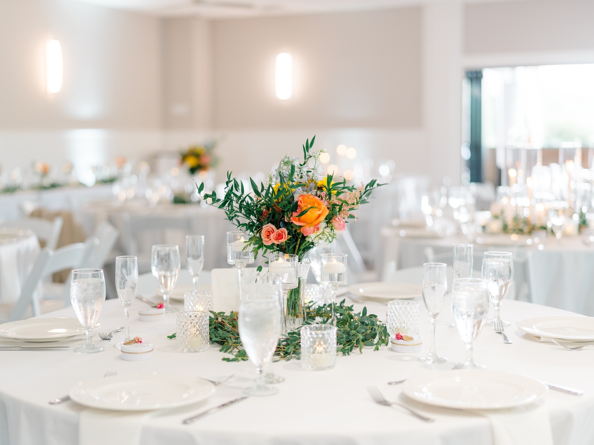 white tables with green and peach flowers centerpiece