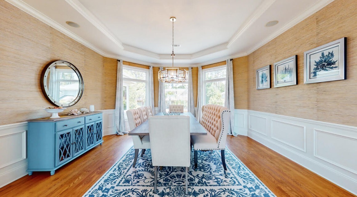 furnished dining room with brown wallpaper and wainscoting with blue accents