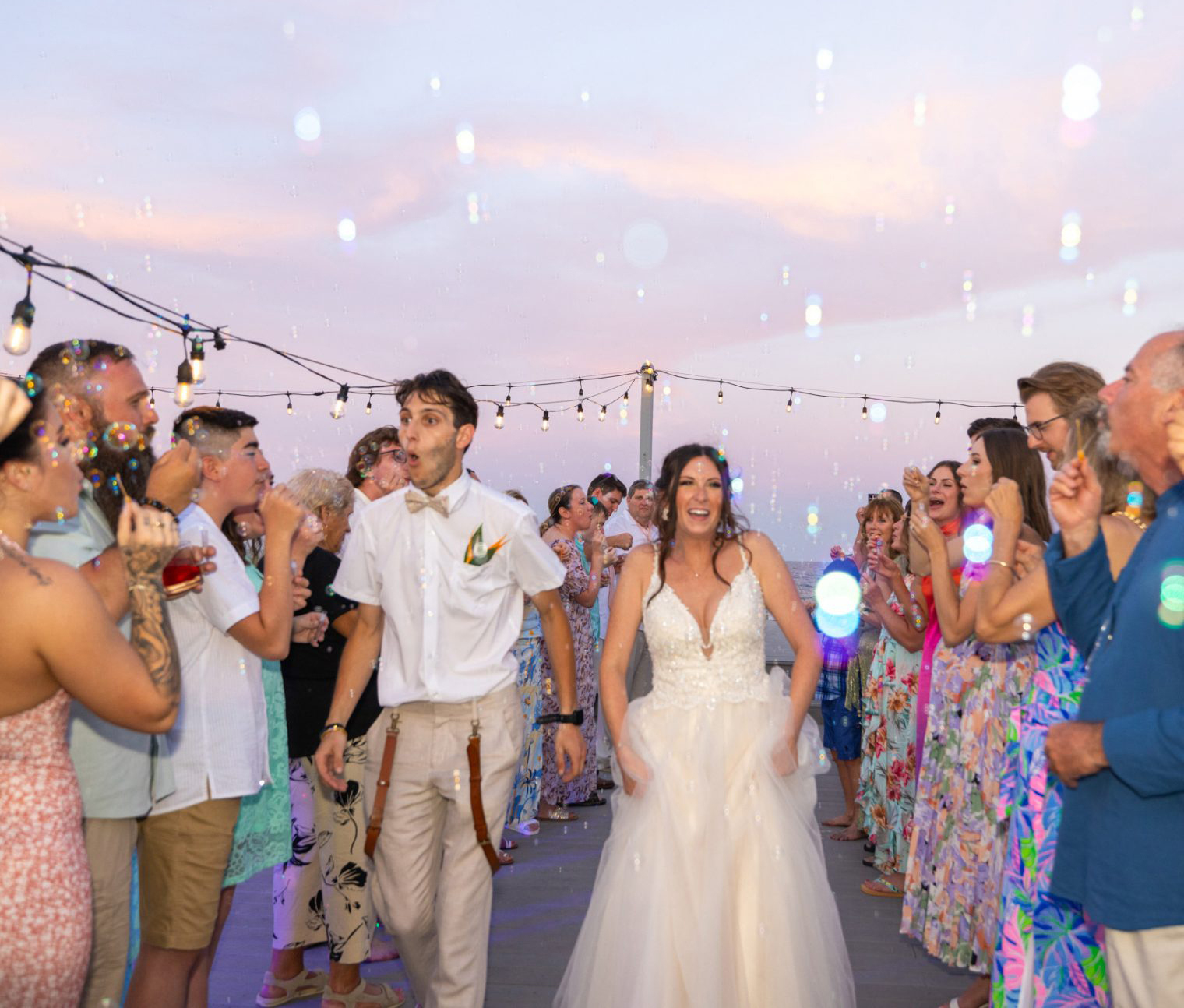 Wedding couple with bubbles sail off at the beach
