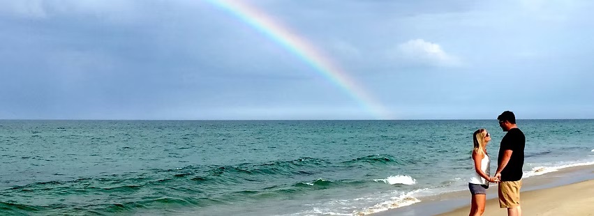 Beach proposal with a rainbow