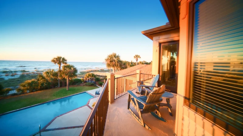 view of the private balcony with Adirondack chairs overlooking the private pool and oceanfront of a vacation rental